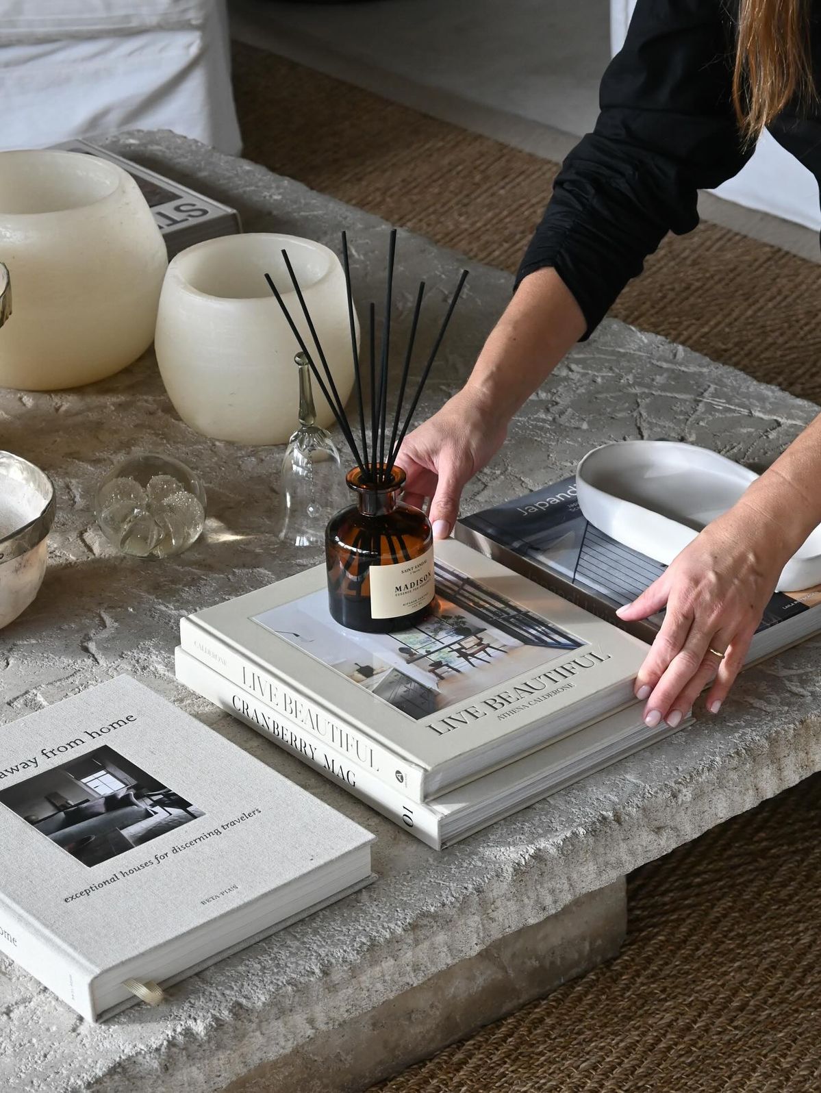 Mesa de pedra com livros, difusor e objetos de decoração numa casa serena