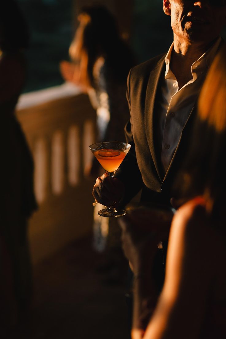 Evento corporativo ao anoitecer, com cocktail em mão e luz quente